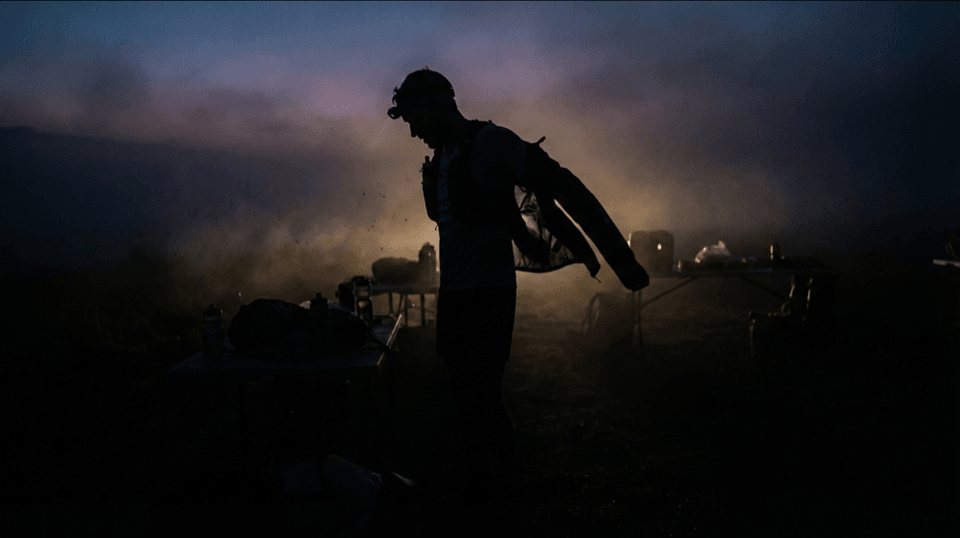 Ultra-trail runner on a night mountain trail lit by a headlamp