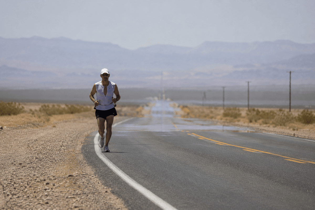 Runner on a sun-exposed road in desert heat, showing the strain of training in very hot conditions