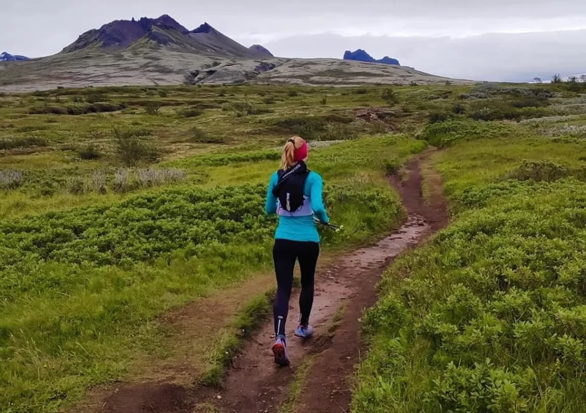 Runner on a winding trail through green Icelandic highlands